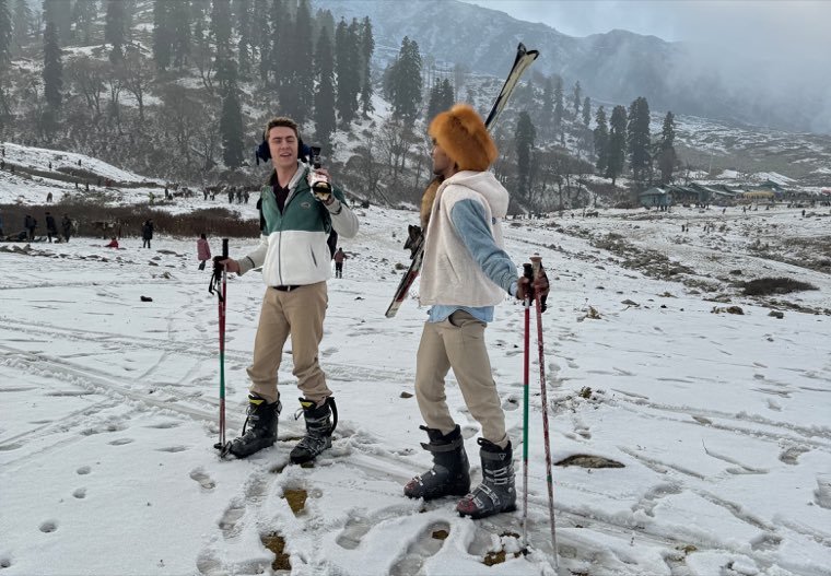 Two friends in ski boots holding poles on a snowy slope