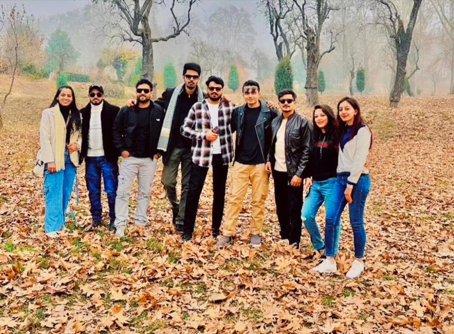 Nine travellers posing on a carpet of autumn chinar leaves